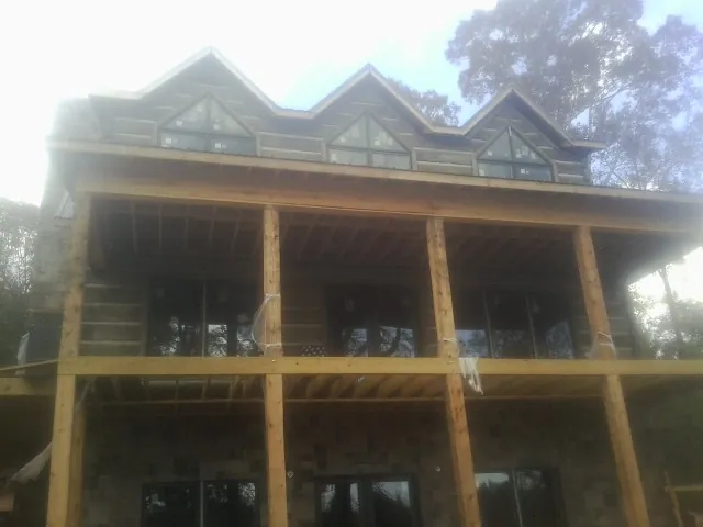 Dormers and porch framing on a large log home under construction — Roof Coating work by our crew in Hartleton