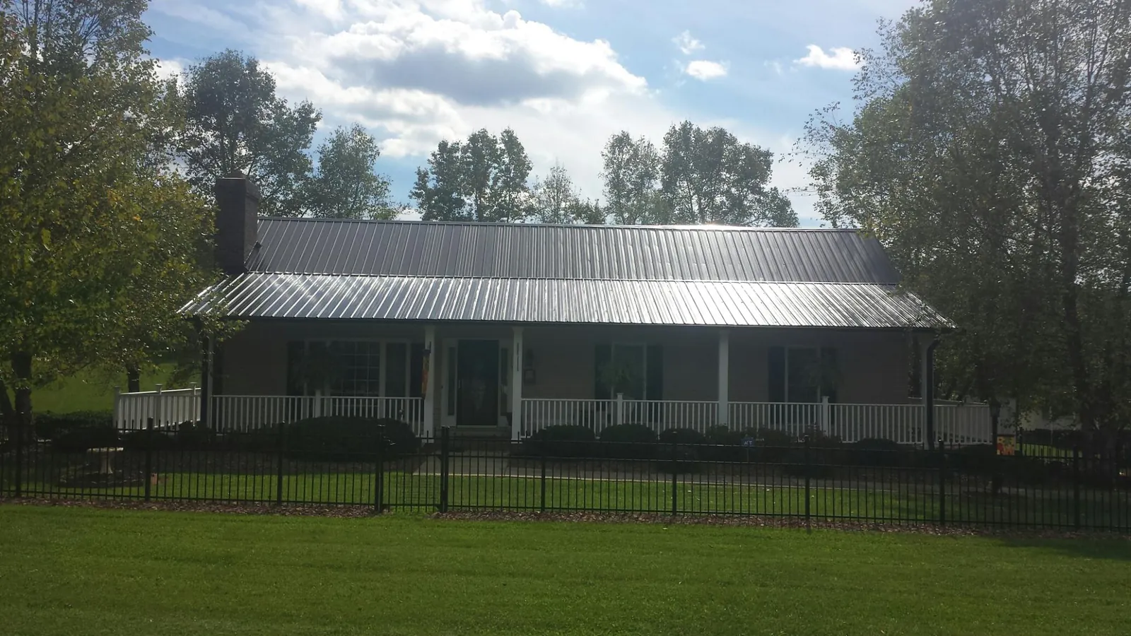 Gray metal roof on a brick ranch with a full width front porch — Gutter Guard Installation work by our crew in Hartleton